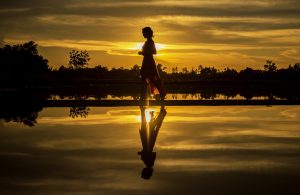Woman walking on beach at dawn